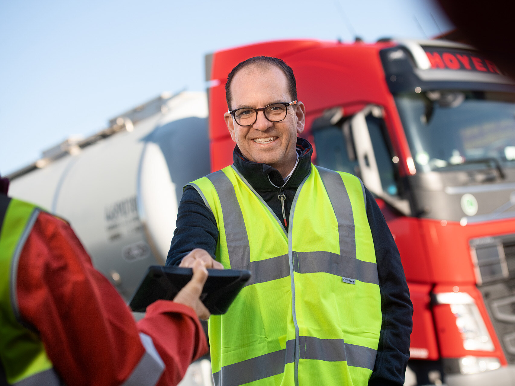 Fahrzeuge HOYER Mitarbeiter mit Warnweste und HOYER Lkw im Hintergrund